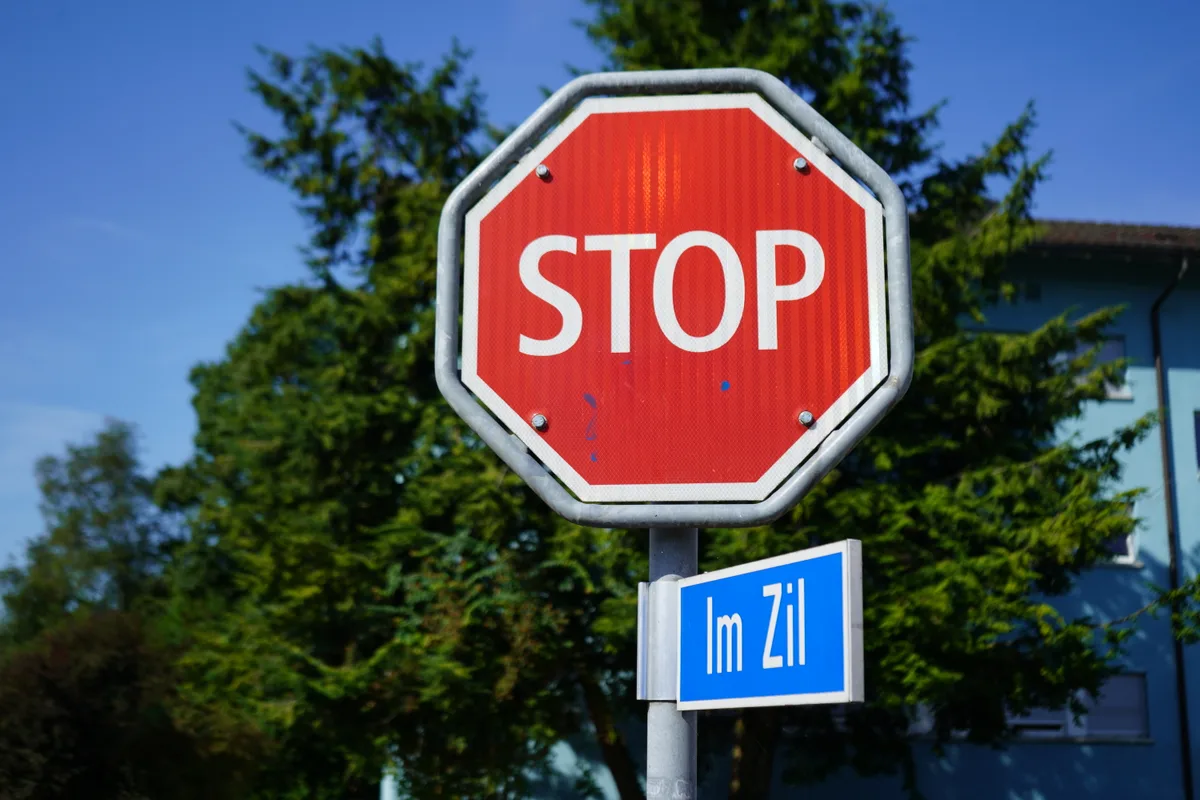 Strassenschild mit Aufschrift «Im Zil», darüber ein Stop-Schild.